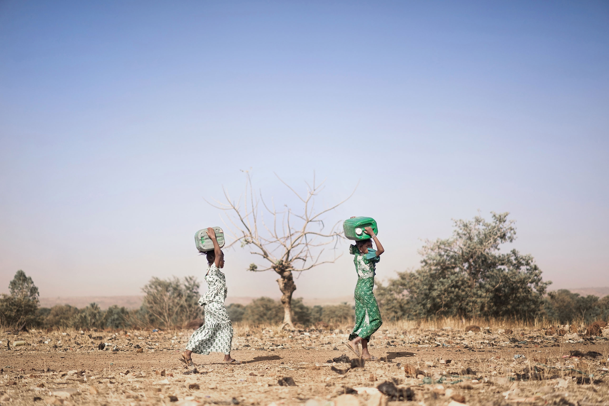 Two women carrying jugs of water on their heads Two women carrying jugs of water on their heads